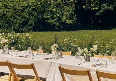 Outdoor tables with linen tablecloths and jars of flowers.