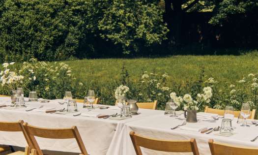 Outdoor tables with linen tablecloths and jars of flowers.