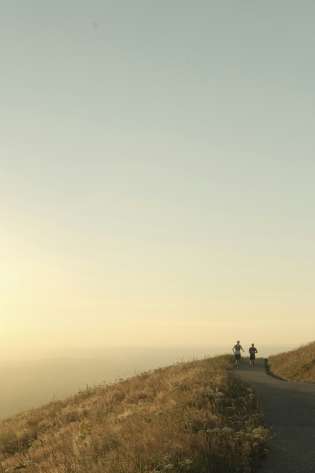 Two people running on hill.