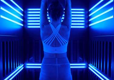 Person stretching in sauna with blue lights .