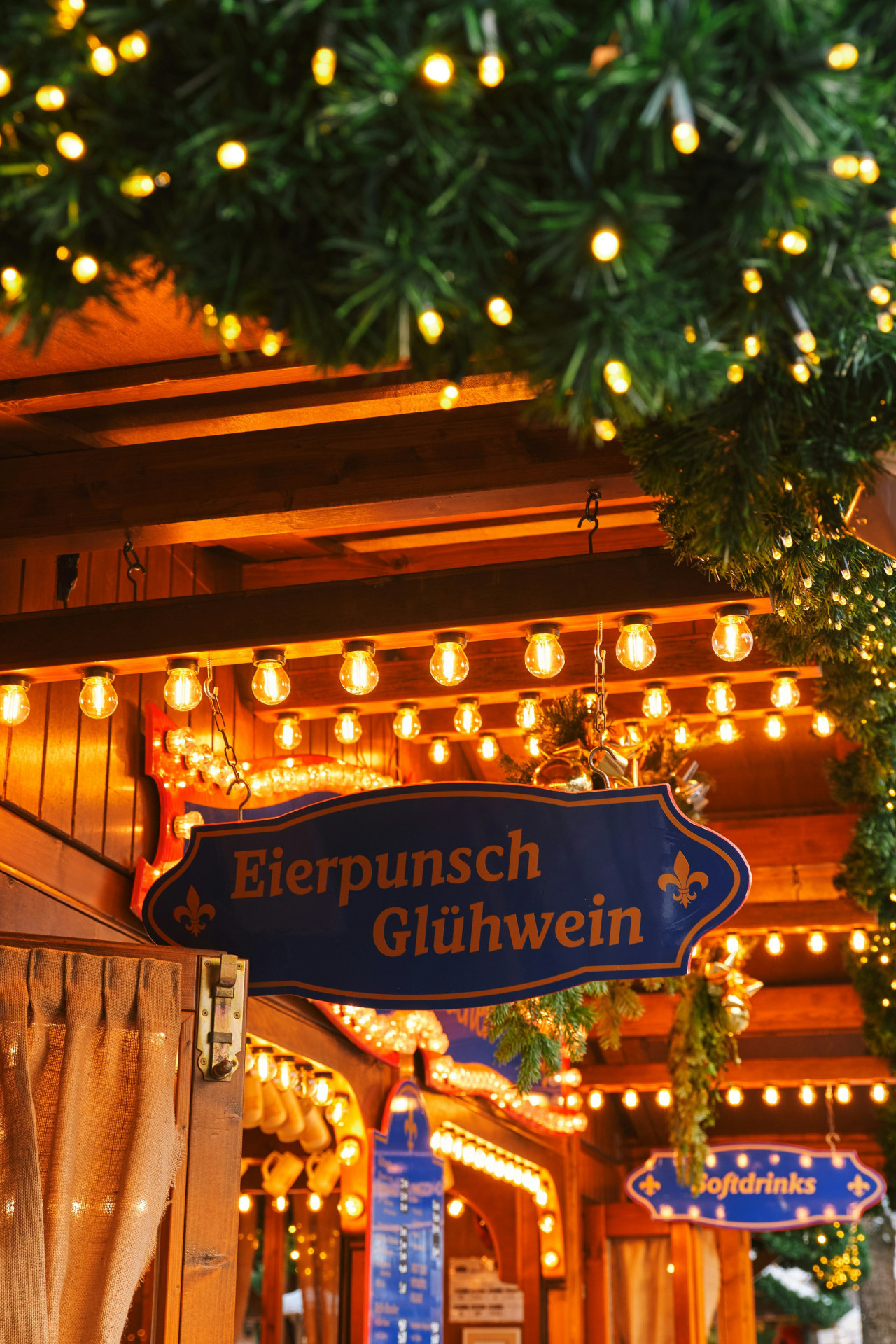 view of christmas market huts with foliage and lights 