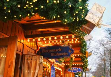 View of christmas market huts with foliage and lights .