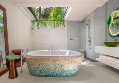 Bath tub covered in blue and cream coloured mosaic tiles.