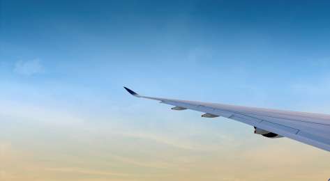 Plane wing with blue sky in the background.