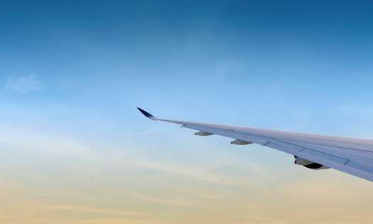Plane wing with blue sky in the background.
