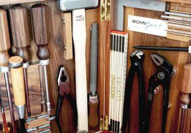 A wooden toolbox contains assorted tools: hammers, chisels, pliers, and clamps, organized neatly.