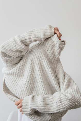 Woman pulling on white jumper.