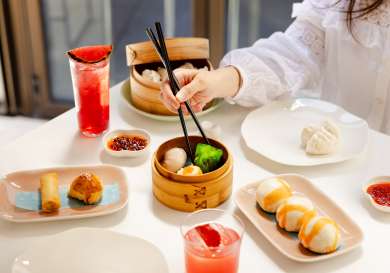 Woman sat at table with dim sum brunch.