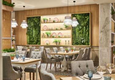 Hotel dining area with statement wall decorated with living plants and pink plates.