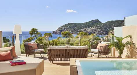 Hotel penthouse balcony area with seating and raised pool.