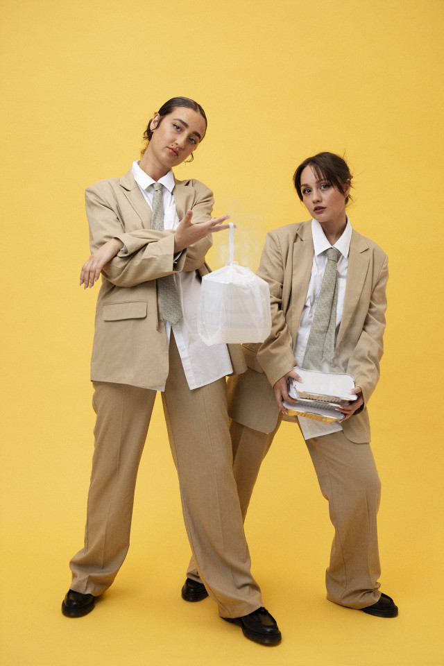 two women posing in matching beige suits