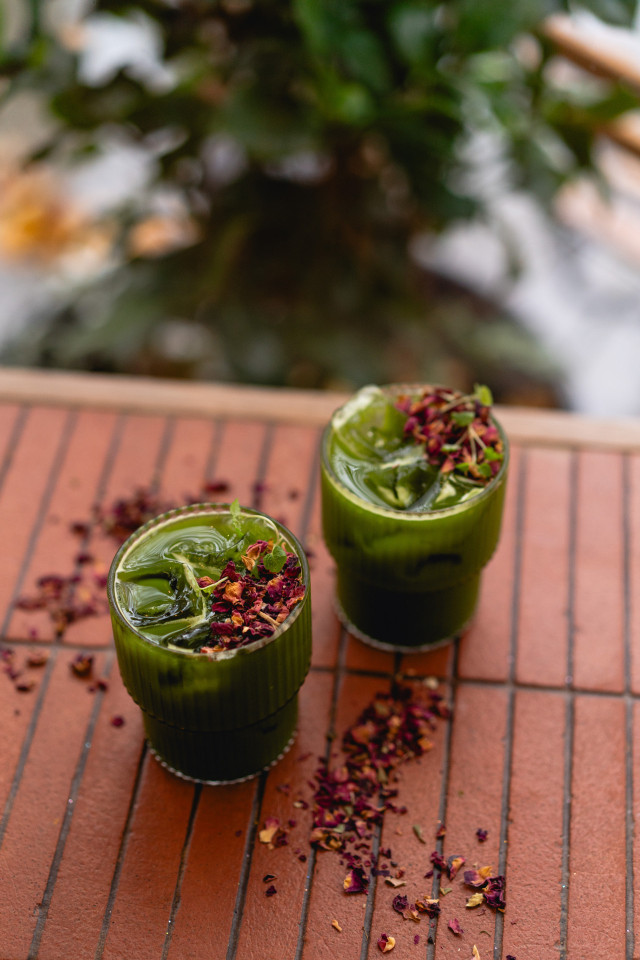 two glasses of matcha topped with ice cubes and dried flowers