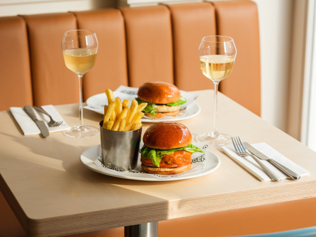 milk burger on white plate with a side of chips and champagne