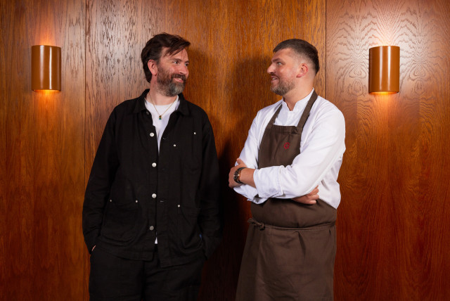 two men smiling at each other inside restaurant 