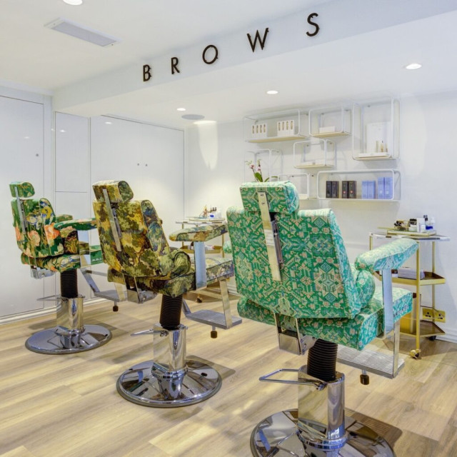 three patterned chairs at salon with 'brows' sign above it