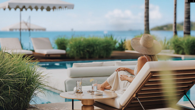 woman sat by the pool in a straw hat 