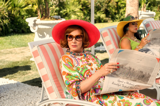 actors on set relaxing on pink striped sun loungers and reading newspaper