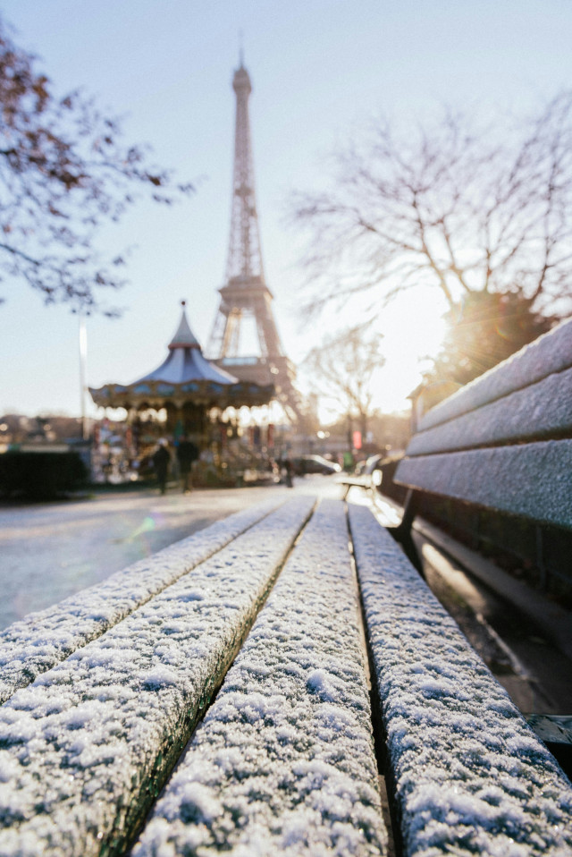 paris bench covered in snow with eiffel tower in the background