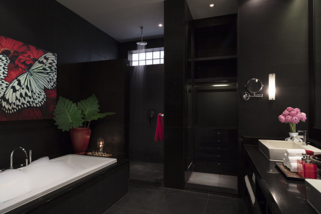 dark hotel bathroom with rainfall shower and bubble bath