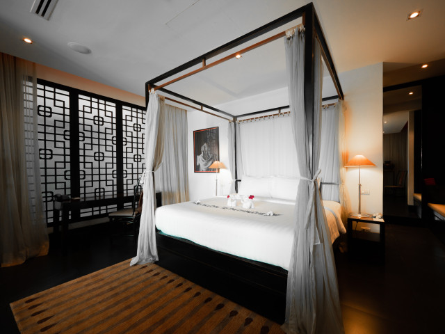 four-postel hotel bed with grey curtains
