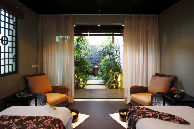 treatment room with two beds, two chairs and an outdoor area filled with plants