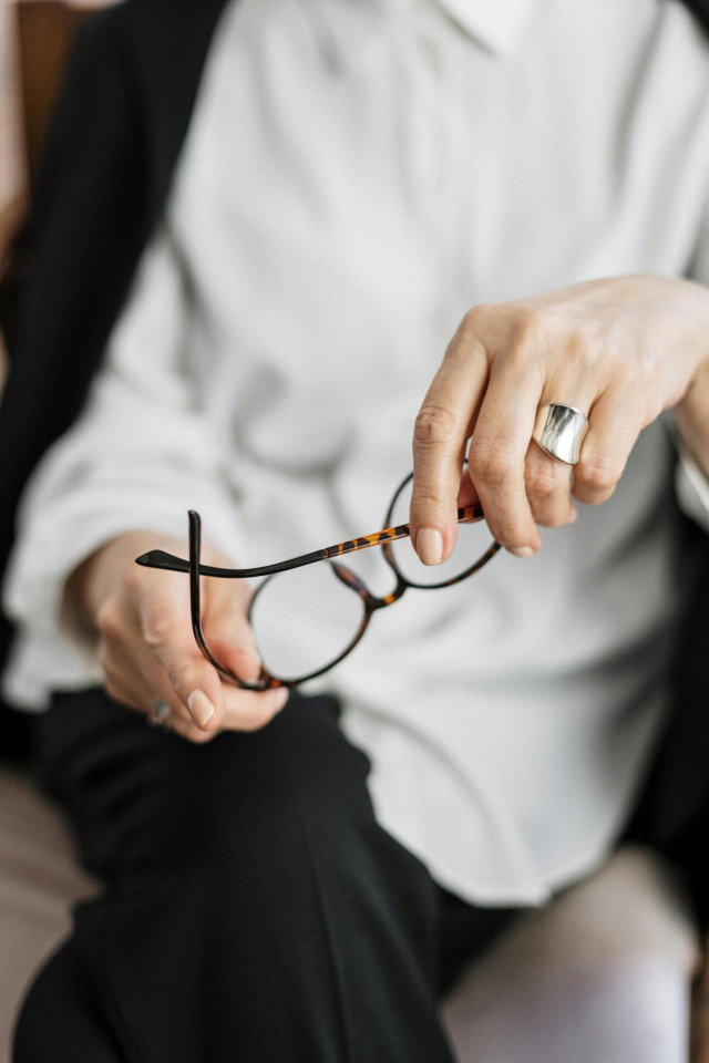 woman holding a pair of glasses while sat on a chair