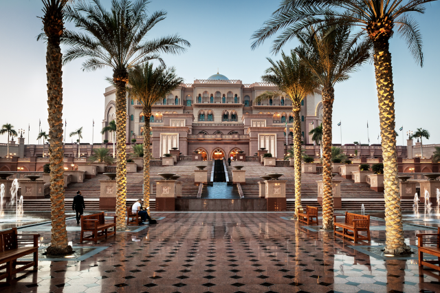 The outside entrance of Emirates Palace, a stunning architectural masterpiece nestled in Abu Dhabi's vibrant cityscape. Majestic domes, exquisite gardens, and a golden façade reflect the opulence within.