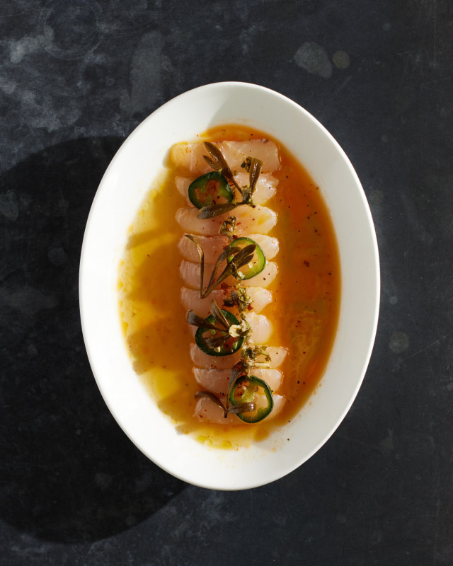 raw fish dish with sauce and slices of jalapeno