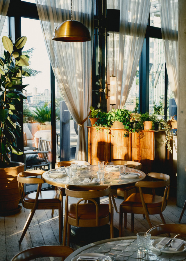 round table at rooftop restaurant with brass lamp hanging above it and sheer curtains in the background