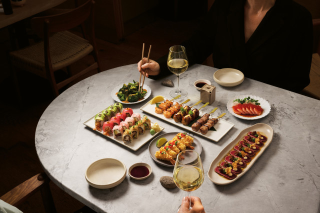 sticks'n'sushi spread on marble table with two glasses of wine