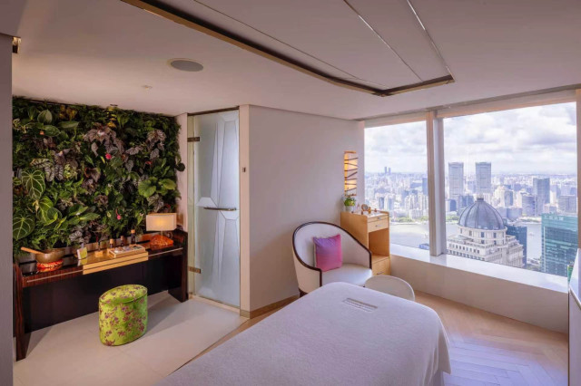 spa treatment room with jungle wallpaper and a cream chair in the corner