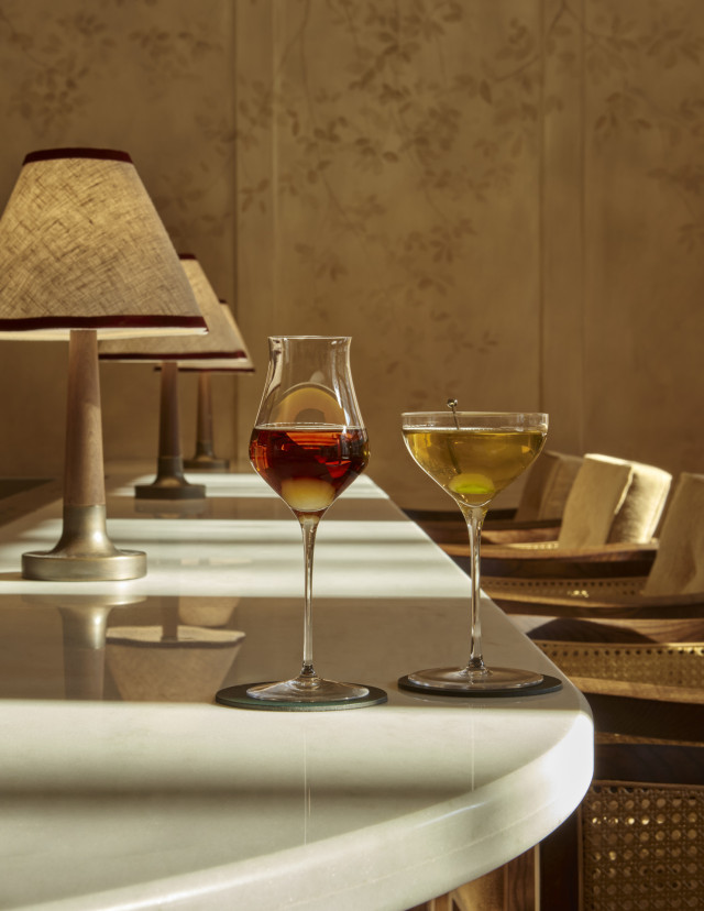 two cocktails on curved bar area with small lamps