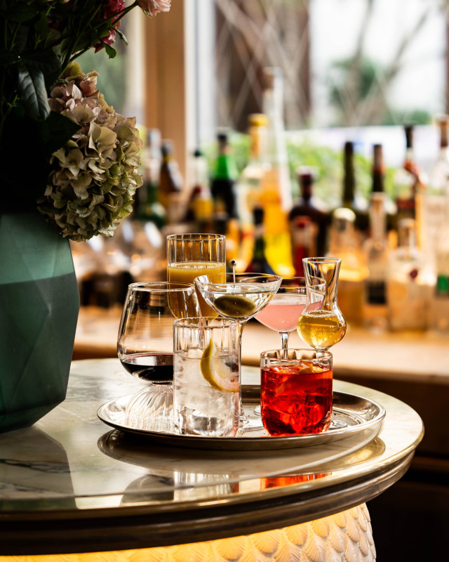 seven cocktails on silver tray in hotel bar