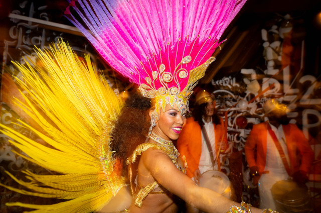 performer wearing pink headdress and feathered yellow outfit