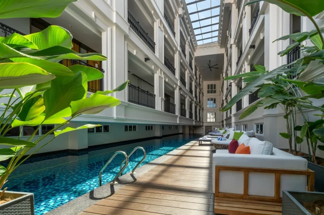 swimming pool inside hotel with white sofas on wooden decking