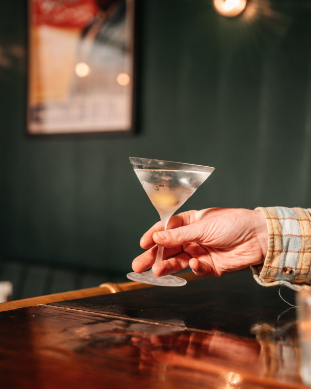 person holding chilled martini glass in bar