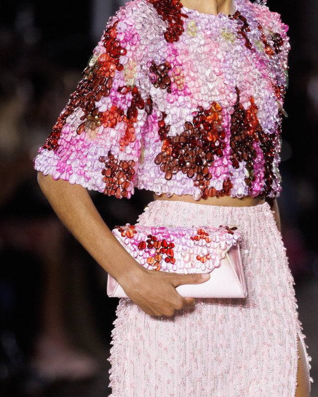 model wearing pink outfit and carrying matching pink satin bag 