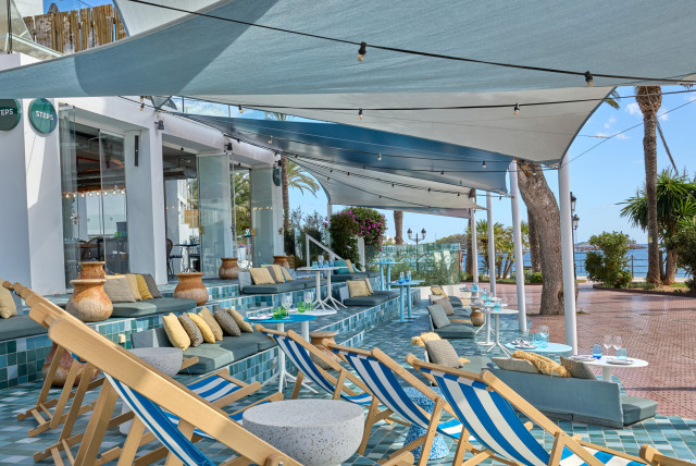outdoor ibiza hotel bar area with deckchairs, blue tiles and awnings