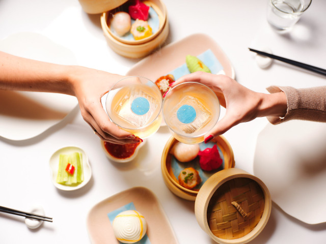 two people clinking glasses over dim sum brunch